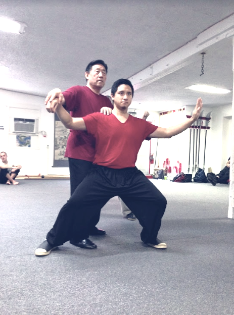 Peter Wu receiving hands-on posture correction from his teacher during training